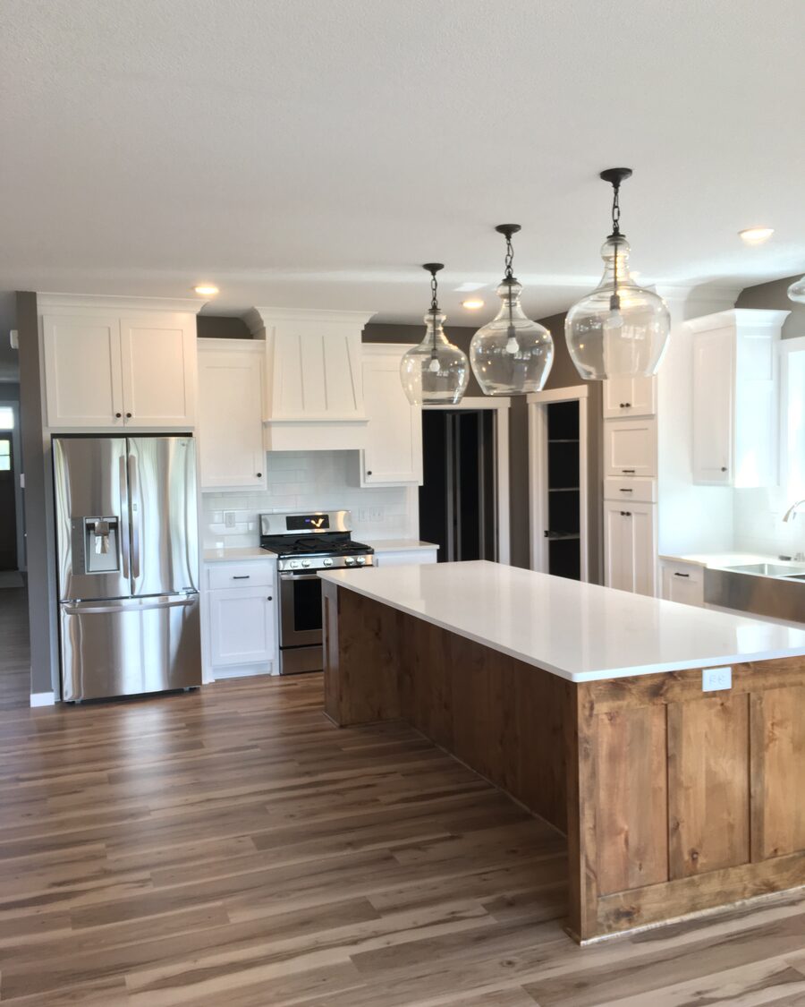 White kitchen with a long stained island and glass pendant lights