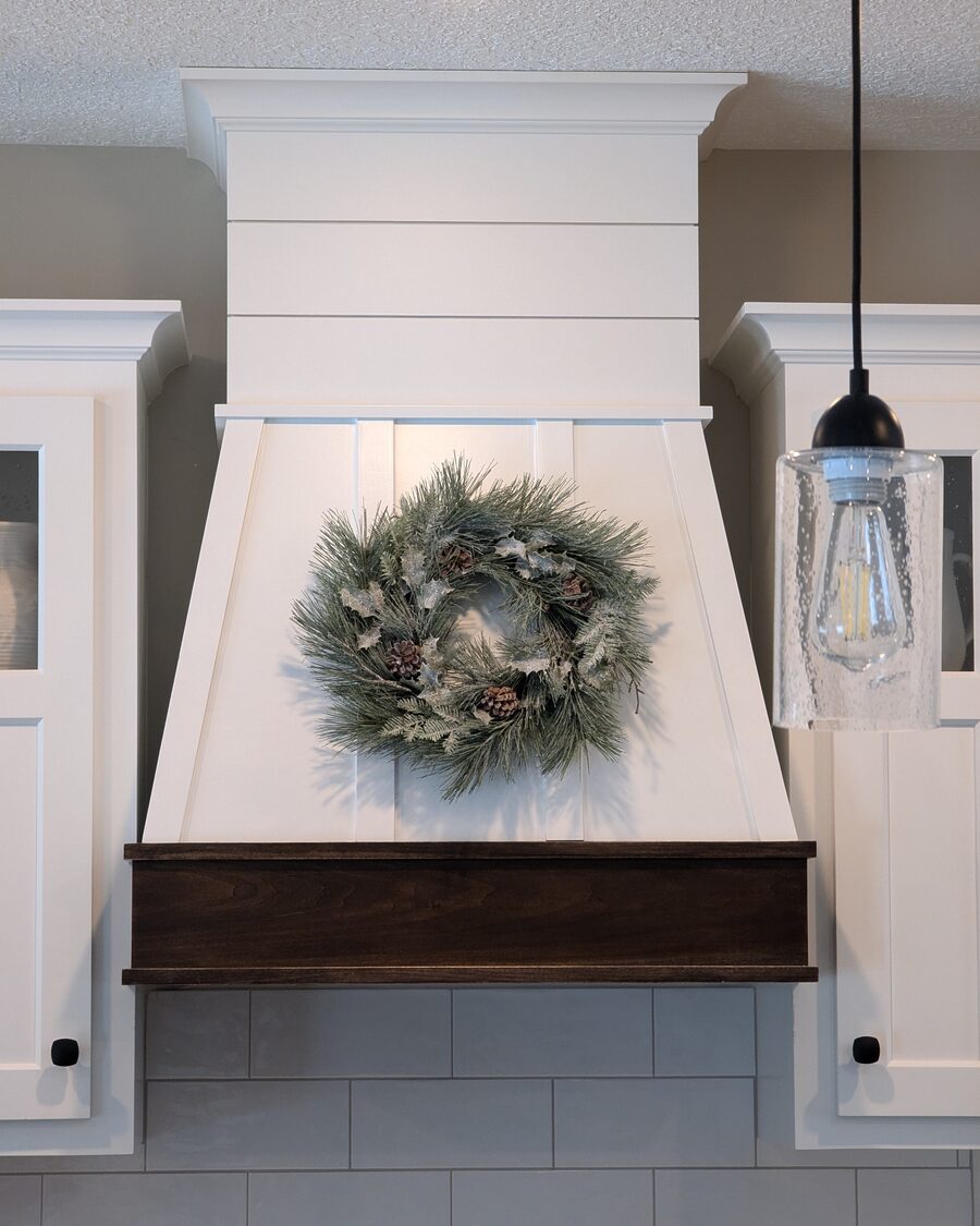 White tapered range hood with a stained wood band